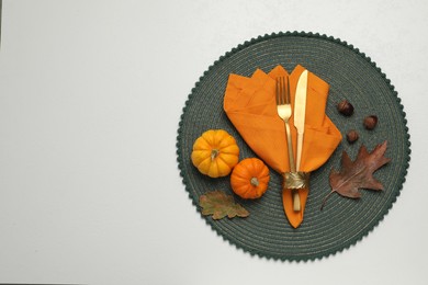 Photo of Cutlery, napkin and autumn decoration on white background, flat lay with space for text. Table setting