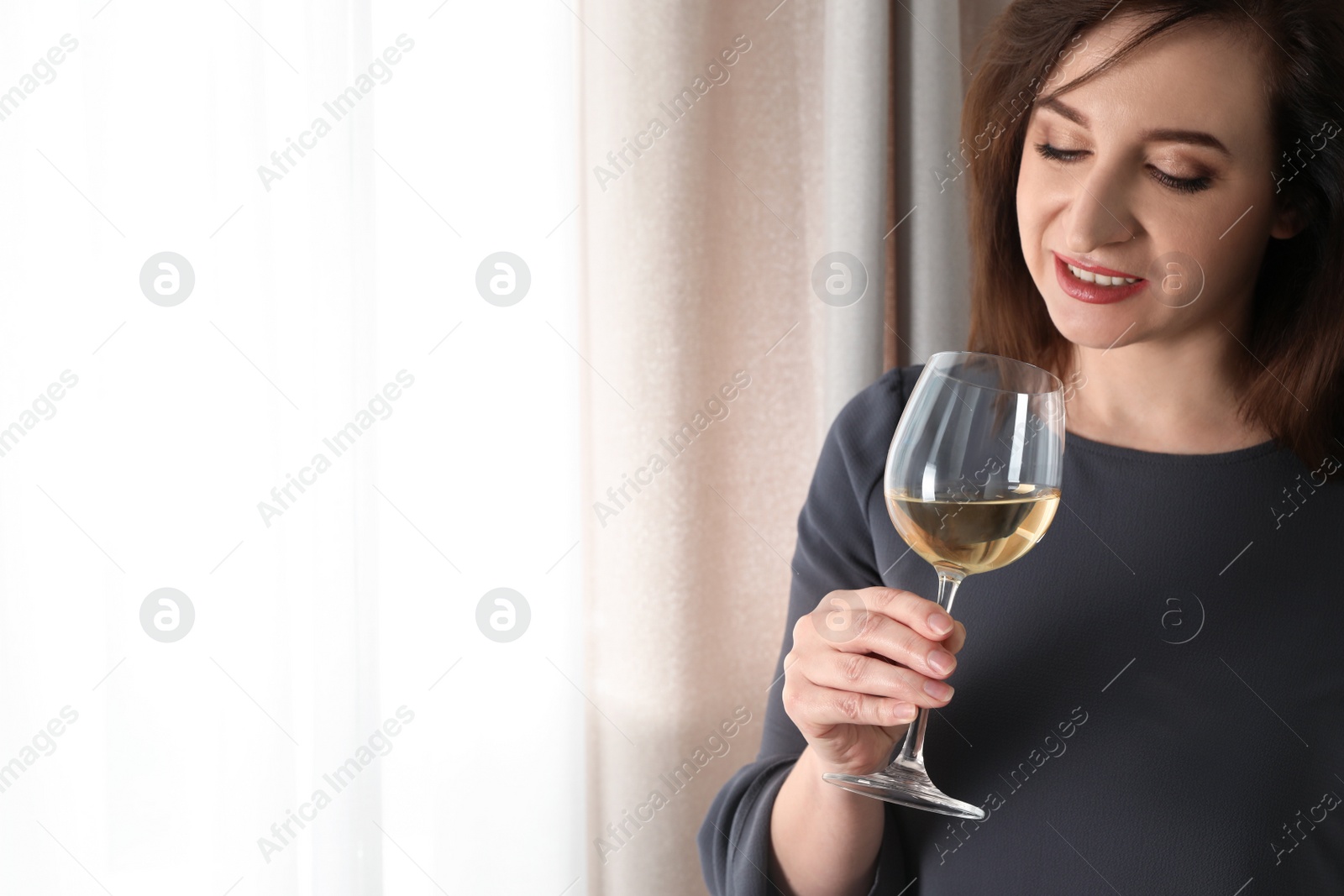 Photo of Woman with glass of wine indoors. Space for text