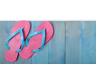 Photo of Pink flip flops and space for text on turquoise wooden table against white background, top view