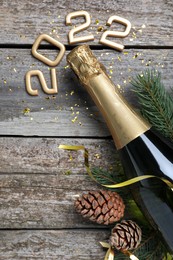 Photo of Happy New Year 2022! Flat lay composition with bottle of sparkling wine on wooden table