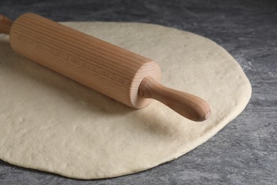 Photo of Raw dough and rolling pin on grey table