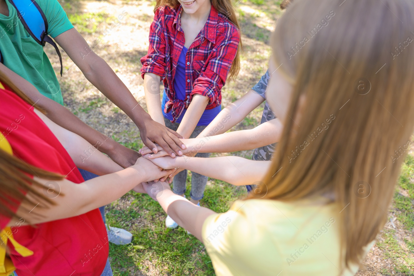 Photo of Group of children putting hands together outdoors. Summer camp