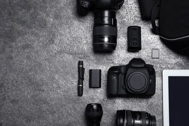 Photo of Professional photography equipment and backpack on grey stone table, flat lay. Space for text
