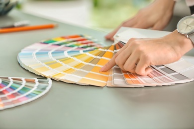 Photo of Female designer working with color palette samples at table