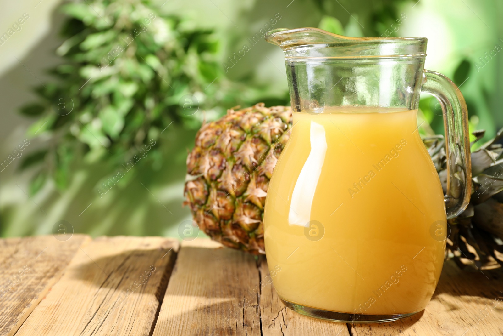 Photo of Delicious pineapple juice and fresh fruit on wooden table against blurred background, space for text