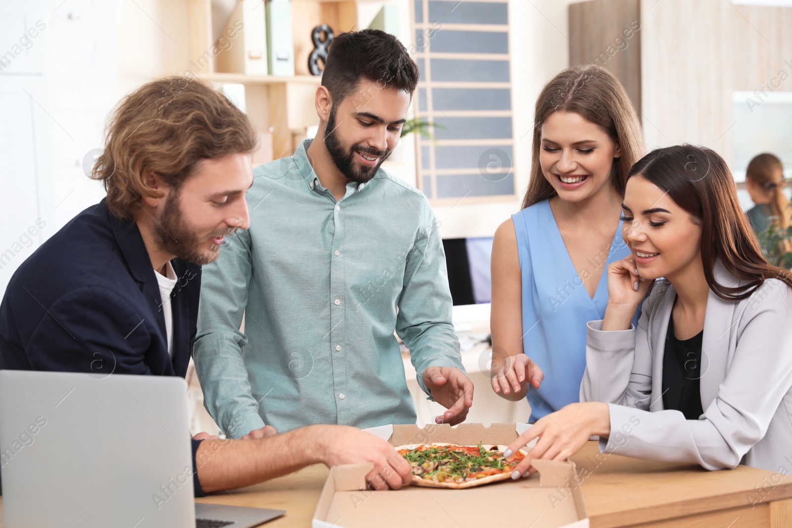 Photo of Office employees having pizza for lunch at workplace. Food delivery