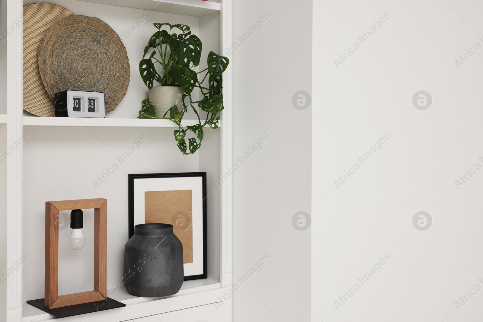 Photo of Shelves with different decor near white wall, space for text. Interior design