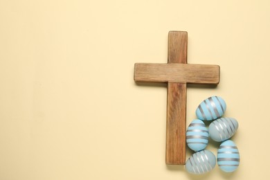 Photo of Wooden cross and painted Easter eggs on beige background, flat lay. Space for text