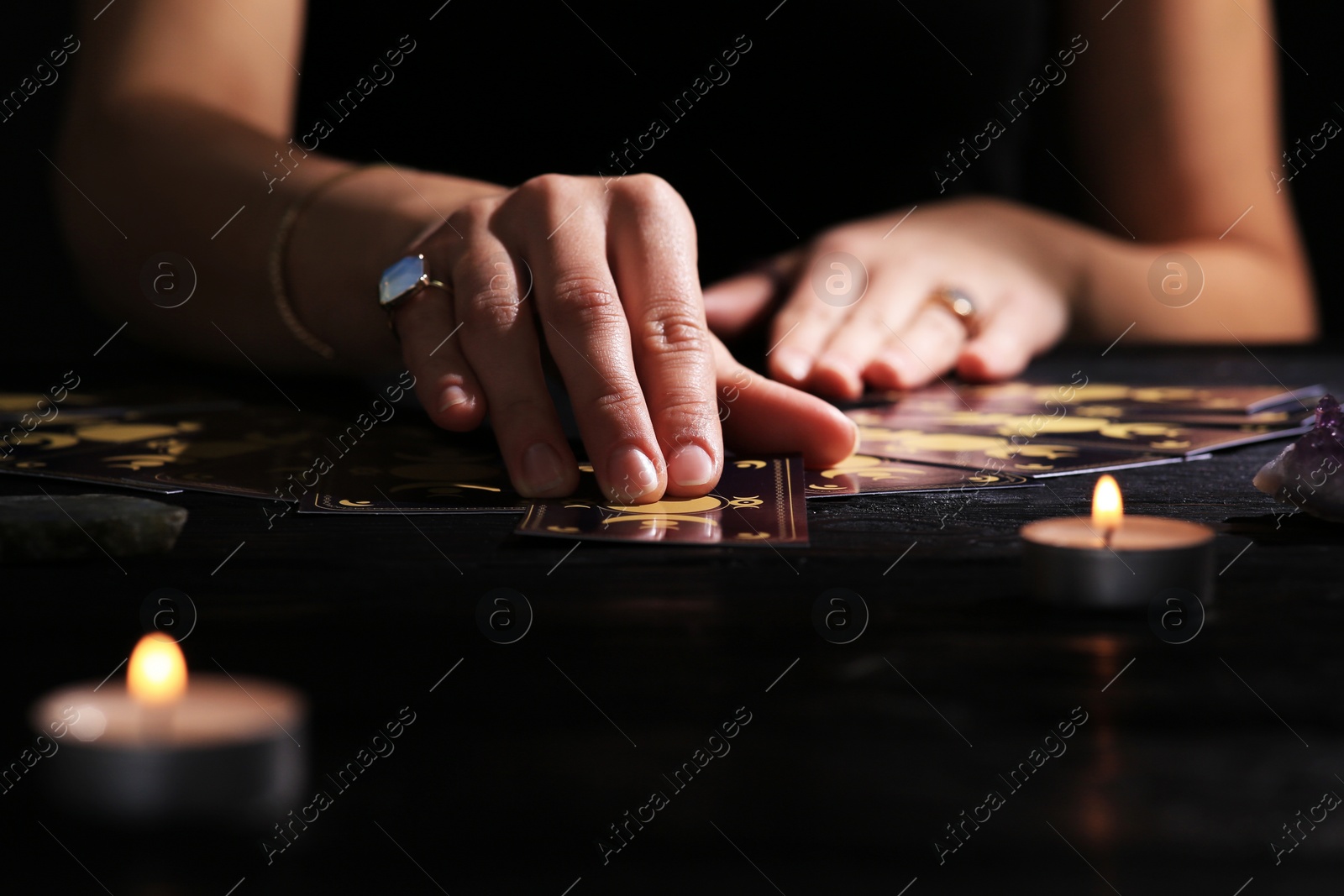 Photo of Soothsayer predicting future with tarot cards at table in darkness, closeup