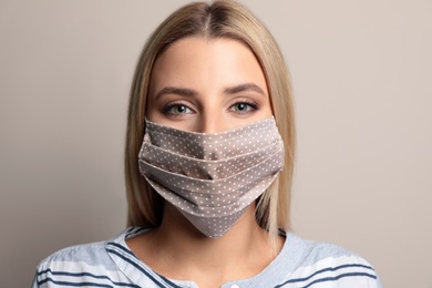 Photo of Young woman in protective face mask on beige background
