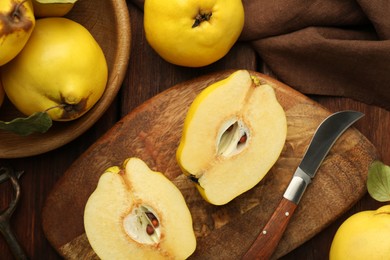 Photo of Tasty ripe quince fruits, peeler and knife on wooden table, flat lay