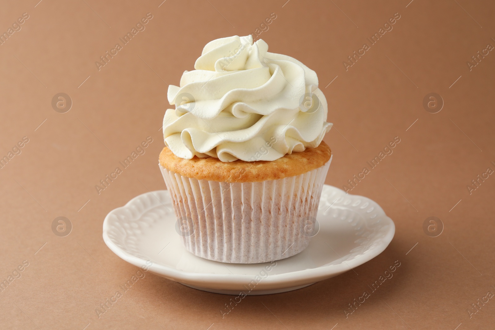 Photo of Tasty vanilla cupcake with cream on dark beige background, closeup