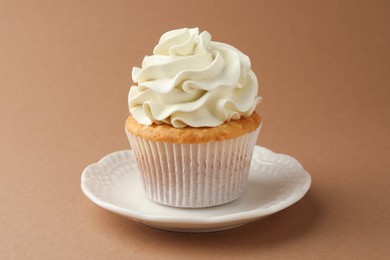 Photo of Tasty vanilla cupcake with cream on dark beige background, closeup