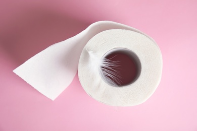 Toilet paper roll with feather on color background, top view