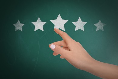 Image of Quality rating. Woman pointing at stars on chalkboard, closeup