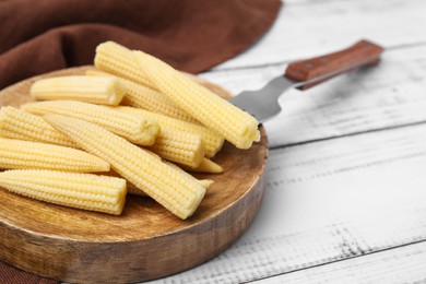 Pickled baby corn and fork on white wooden table, closeup. Space for text