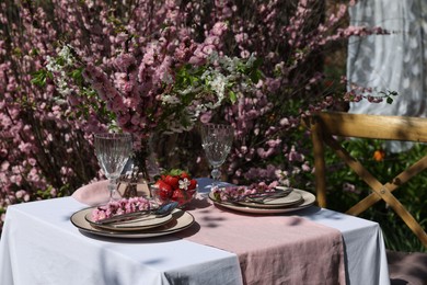 Photo of Stylish table setting with beautiful spring flowers in garden