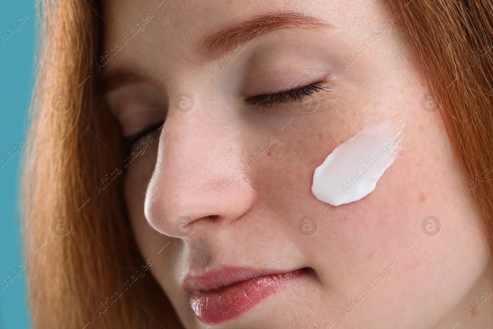 Photo of Beautiful woman with freckles and cream on her face, closeup