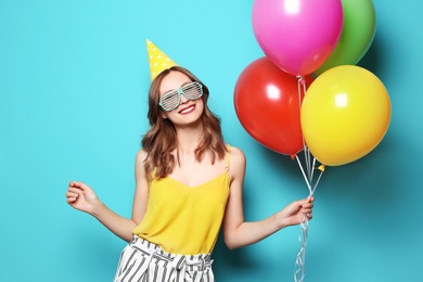 Photo of Young woman with bright balloons on color background. Birthday celebration