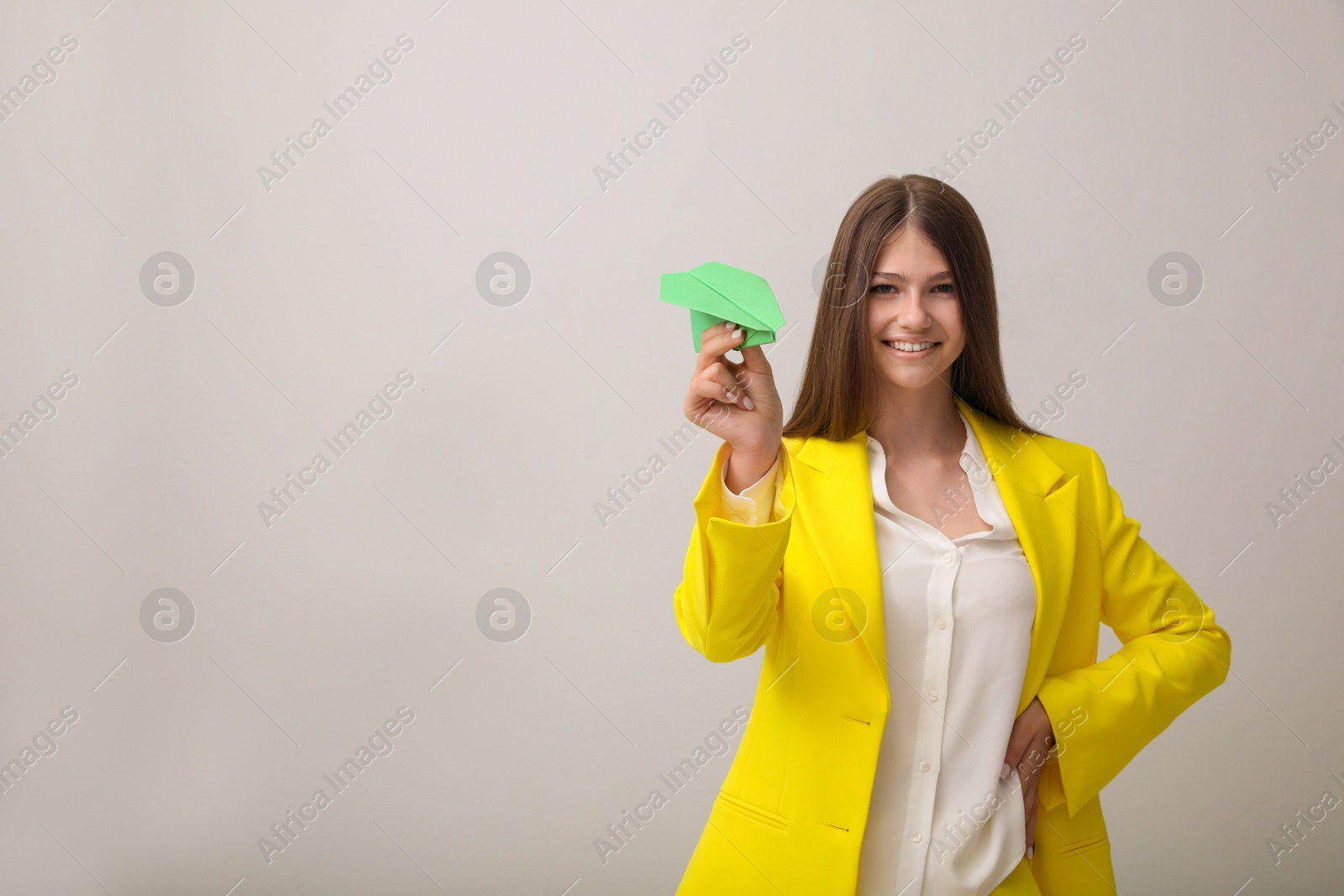 Photo of Beautiful teenage girl with paper plane on grey background. Space for text