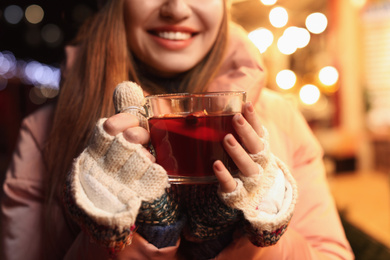 Happy woman with mulled wine at winter fair, closeup