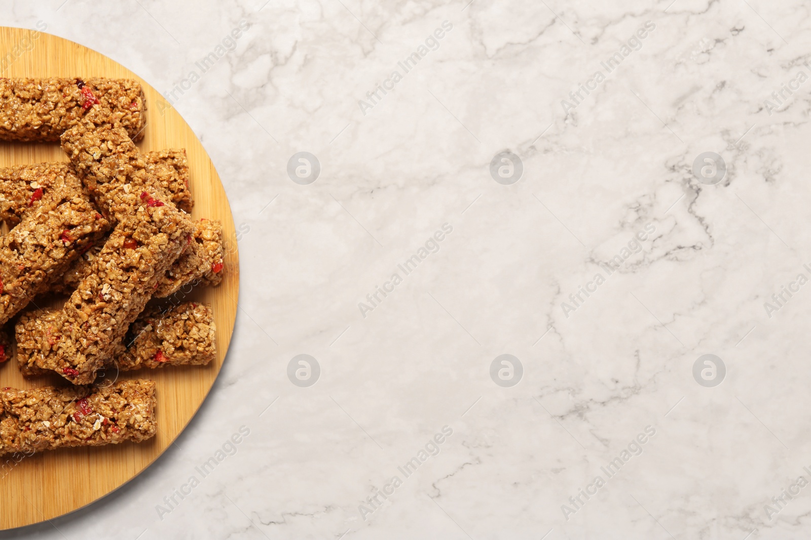 Photo of Tasty granola bars on white marble table, top view. Space for text