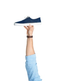 Photo of Young man holding comfortable shoe on white background, closeup