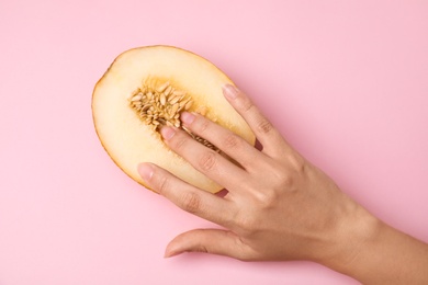 Young woman touching half of melon on pink background, top view. Sex concept