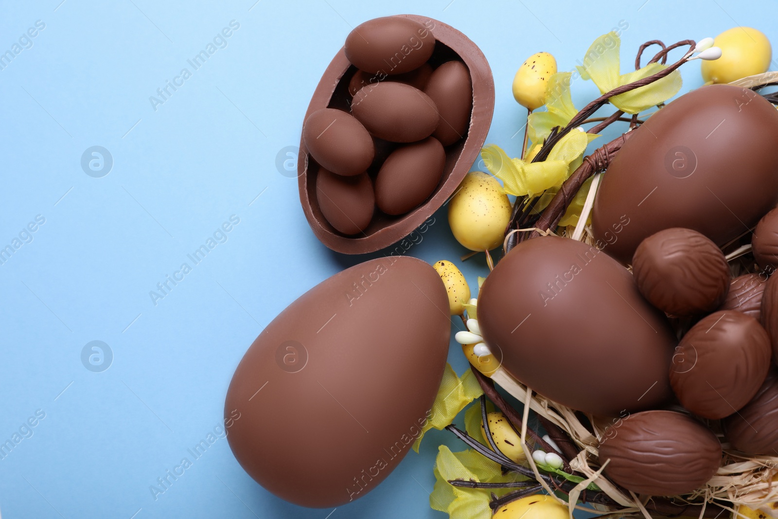 Photo of Delicious chocolate eggs on light blue background, flat lay. Space for text