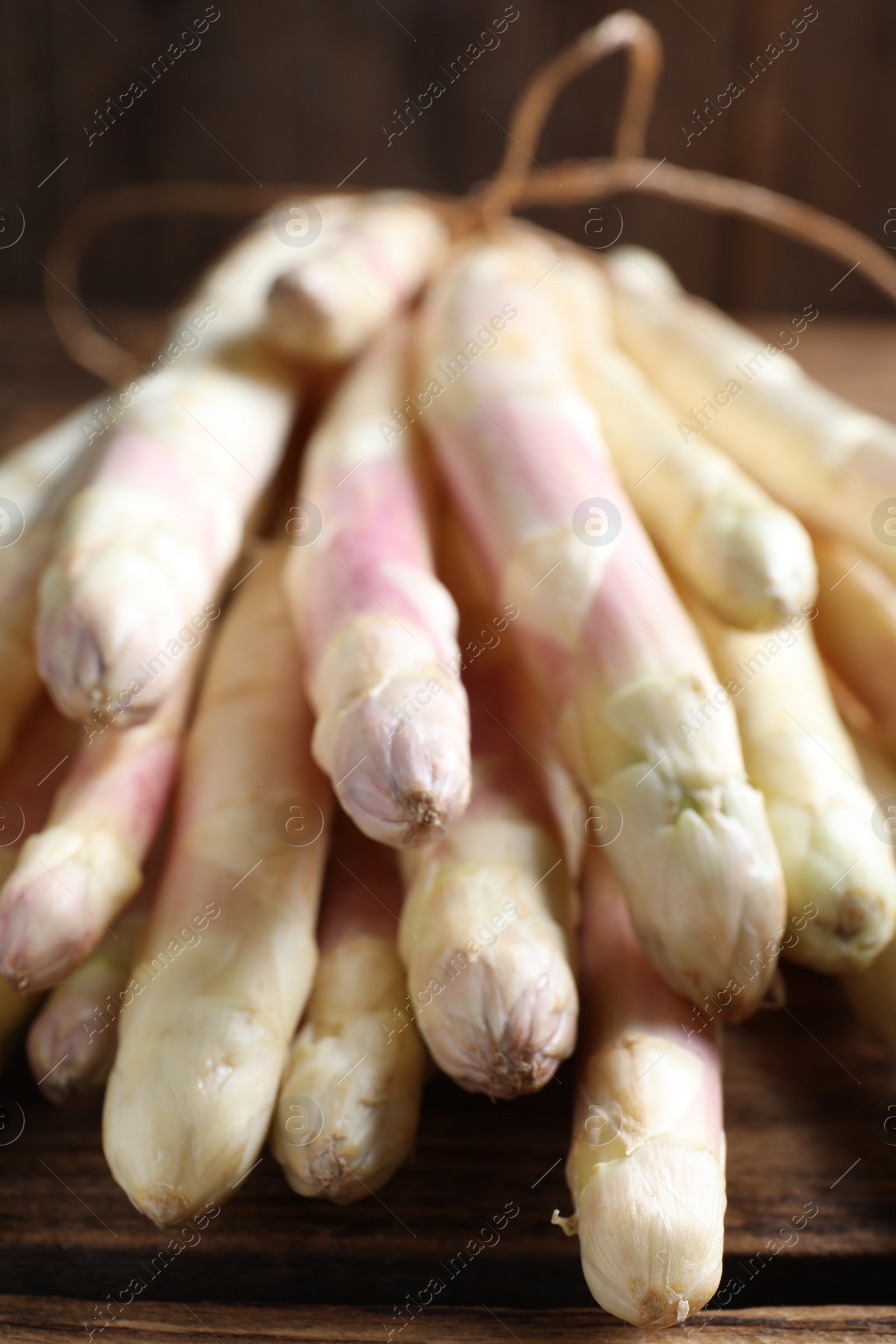 Photo of Bunch of fresh white asparagus on wooden table, closeup