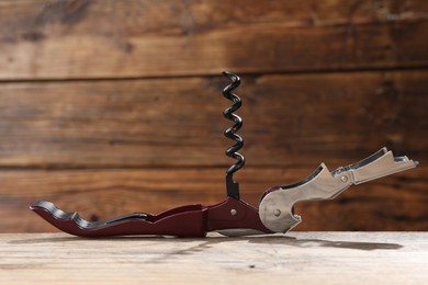 Photo of One corkscrew (sommelier knife) on wooden table, closeup