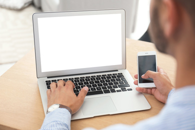 Young man using modern computer at table in office, closeup. Space for design