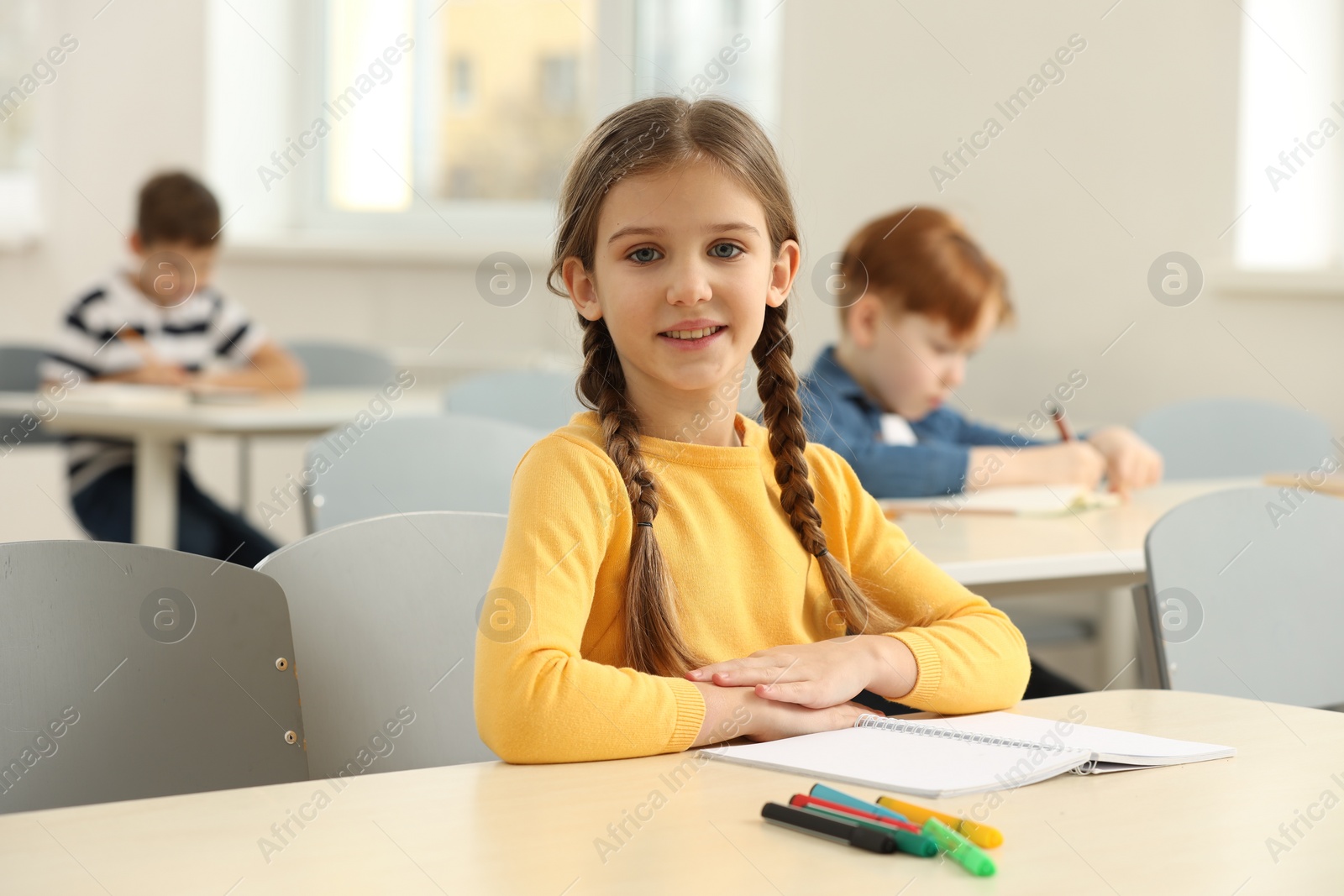 Photo of Portrait of smiling little girl studying in classroom at school