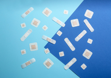 Photo of Different types of sticking plasters on blue background, flat lay