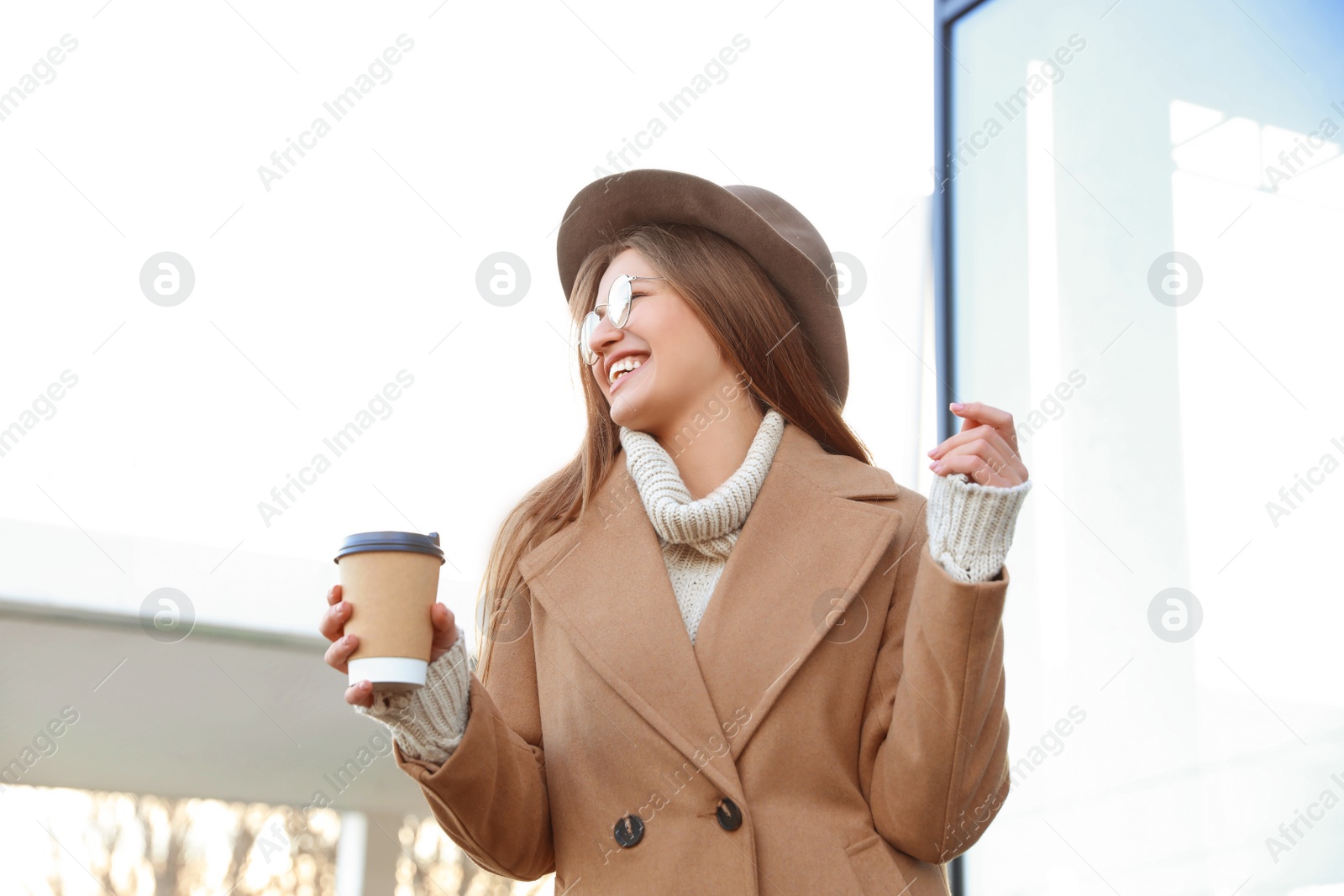 Photo of Young woman with cup of coffee on city street in morning