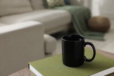 Photo of Ceramic mug of tea and book on wooden table. Mockup for design