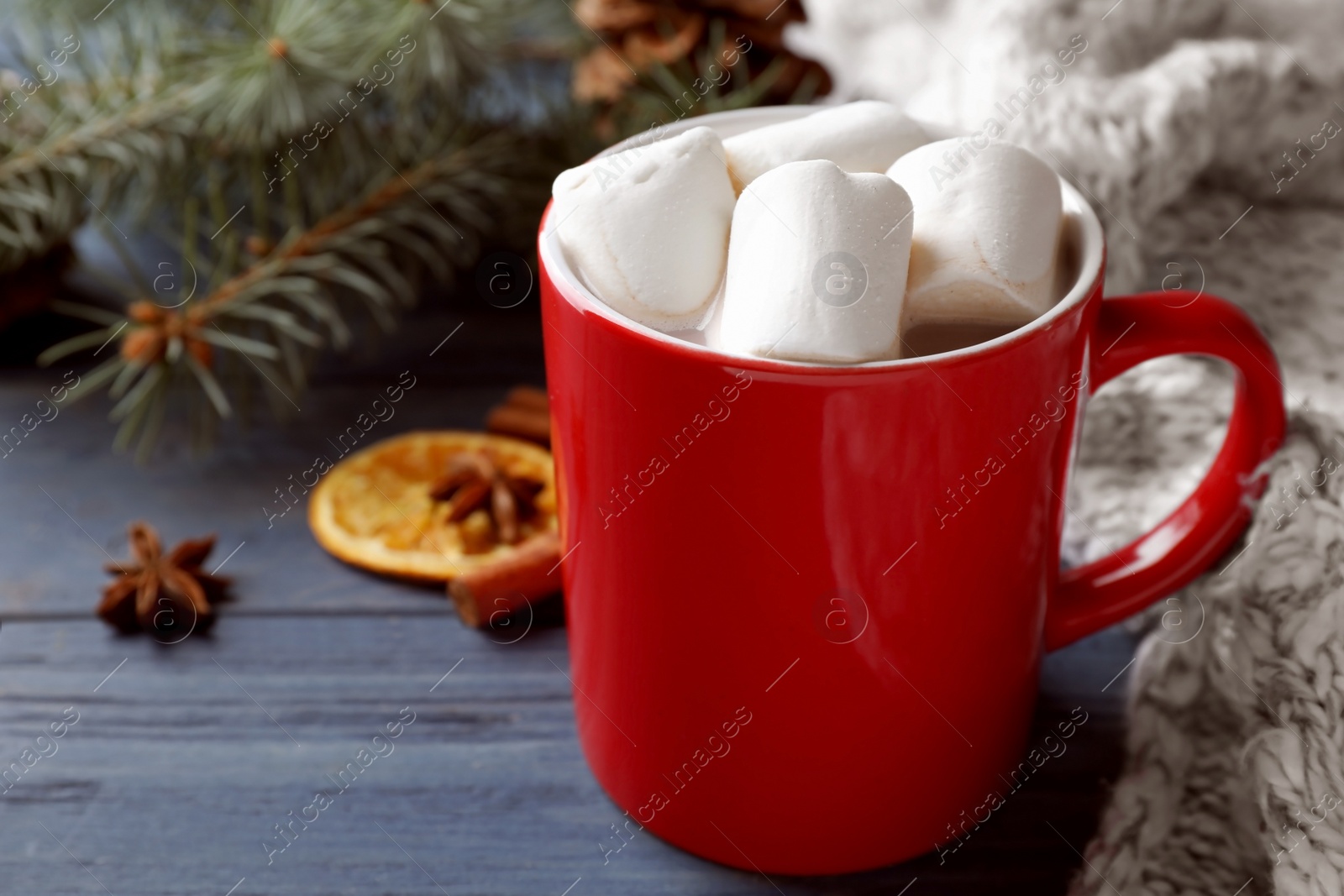 Photo of Composition of tasty cocoa with marshmallows in cup on blue wooden table. Space for text