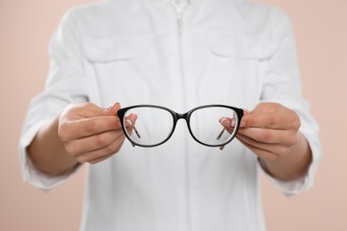 Female ophthalmologist with eyeglasses on light background, closeup