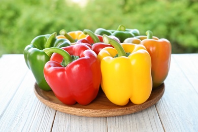 Photo of Plate with ripe paprika peppers on table against blurred background