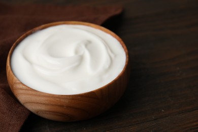 Photo of Delicious natural yogurt in bowl on wooden table, closeup. Space for text