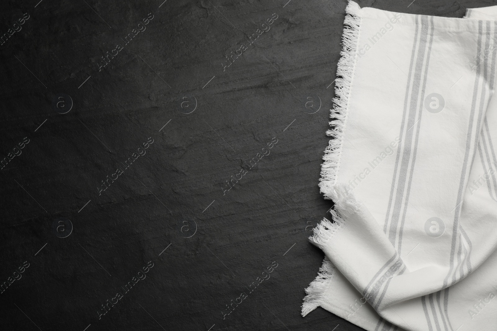 Photo of Striped kitchen towel on black table, top view. Space for text