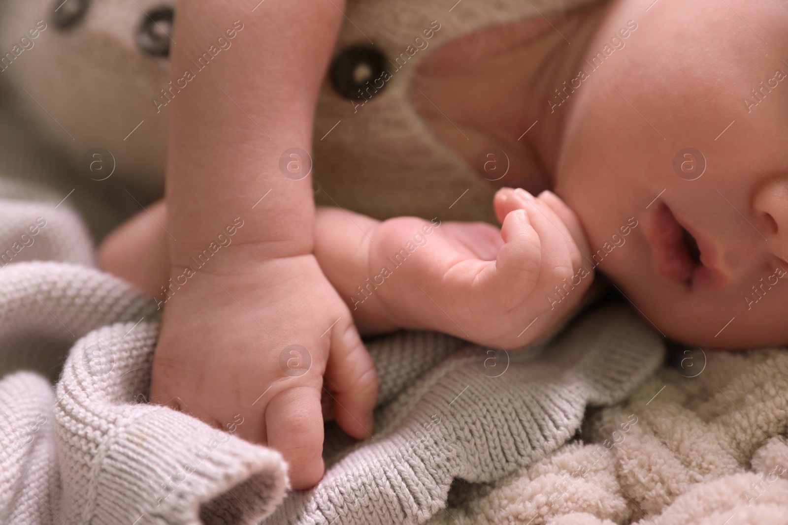 Photo of Cute newborn baby lying on beige crocheted plaid, closeup