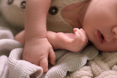 Photo of Cute newborn baby lying on beige crocheted plaid, closeup