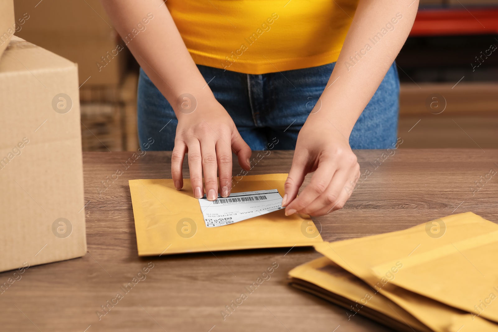 Photo of Post office worker sticking barcode on parcel at counter indoors, closeup