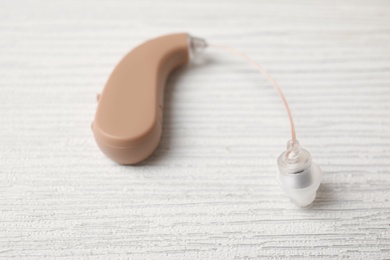 Photo of Hearing aid on white wooden table, closeup