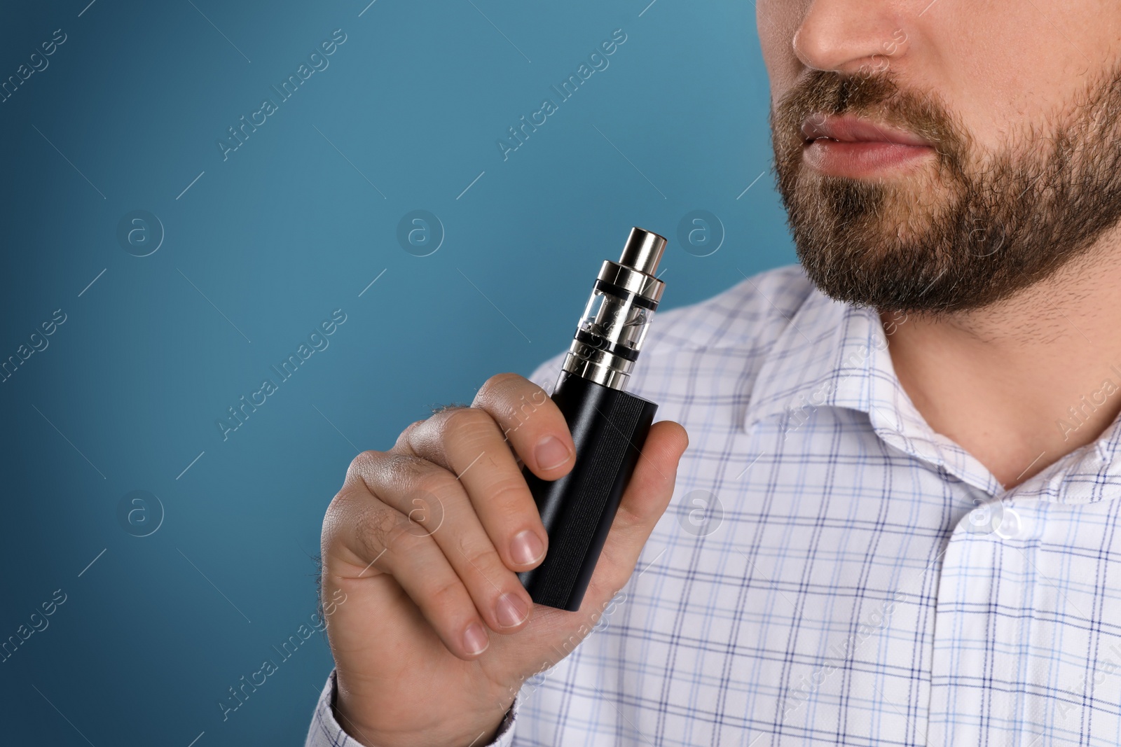 Photo of Man using electronic cigarette on light blue background, closeup