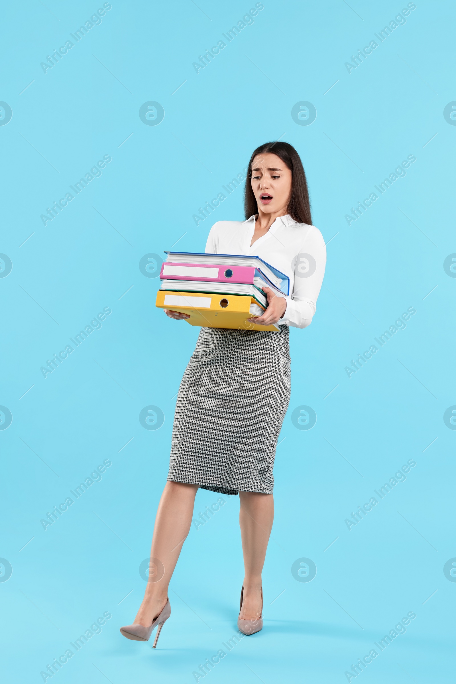 Photo of Frustrated woman with folders on light blue background