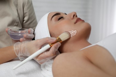 Photo of Young woman during face peeling procedure in salon