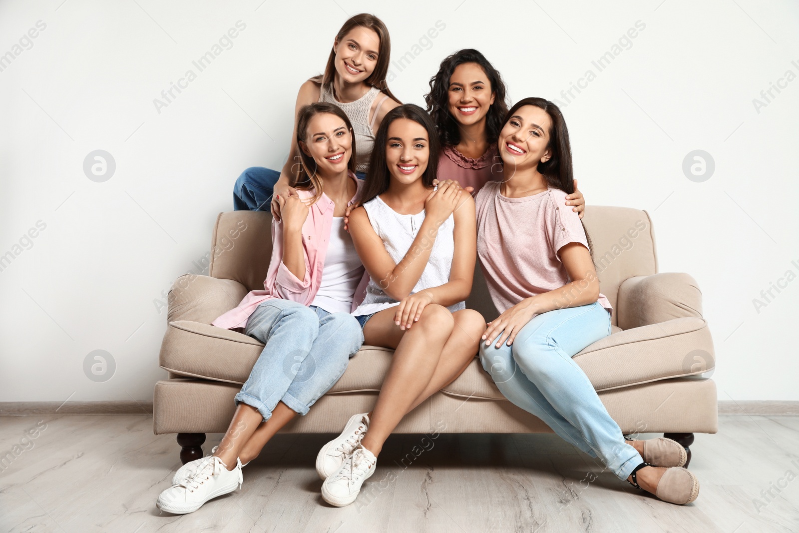 Photo of Happy women sitting on sofa near white wall. Girl power concept