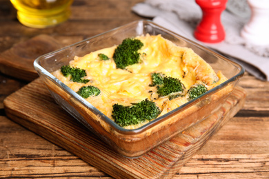 Tasty broccoli casserole in baking dish on wooden table